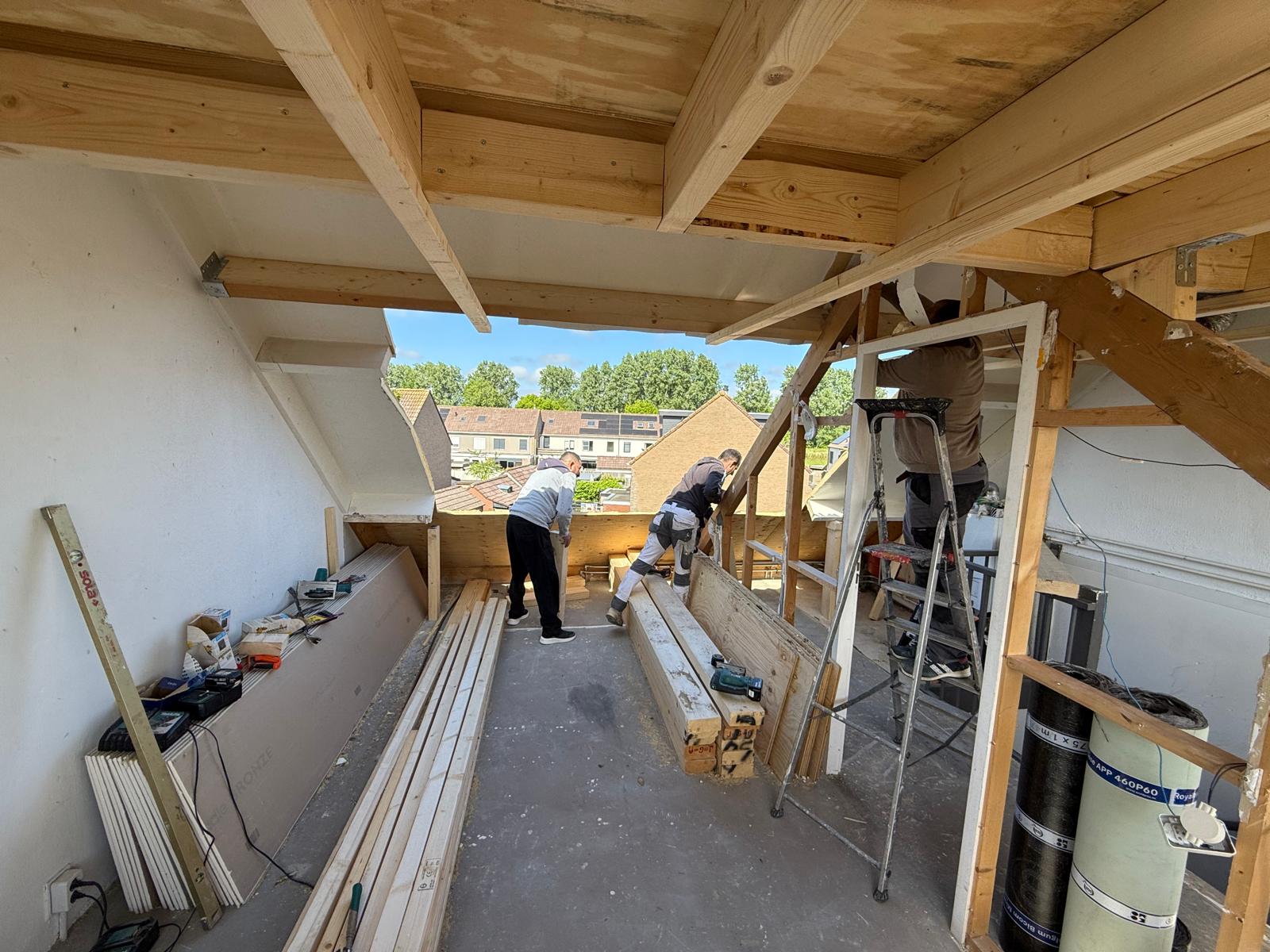 Vakman aan het werk in een dakopbouw met houten balkconstructie
