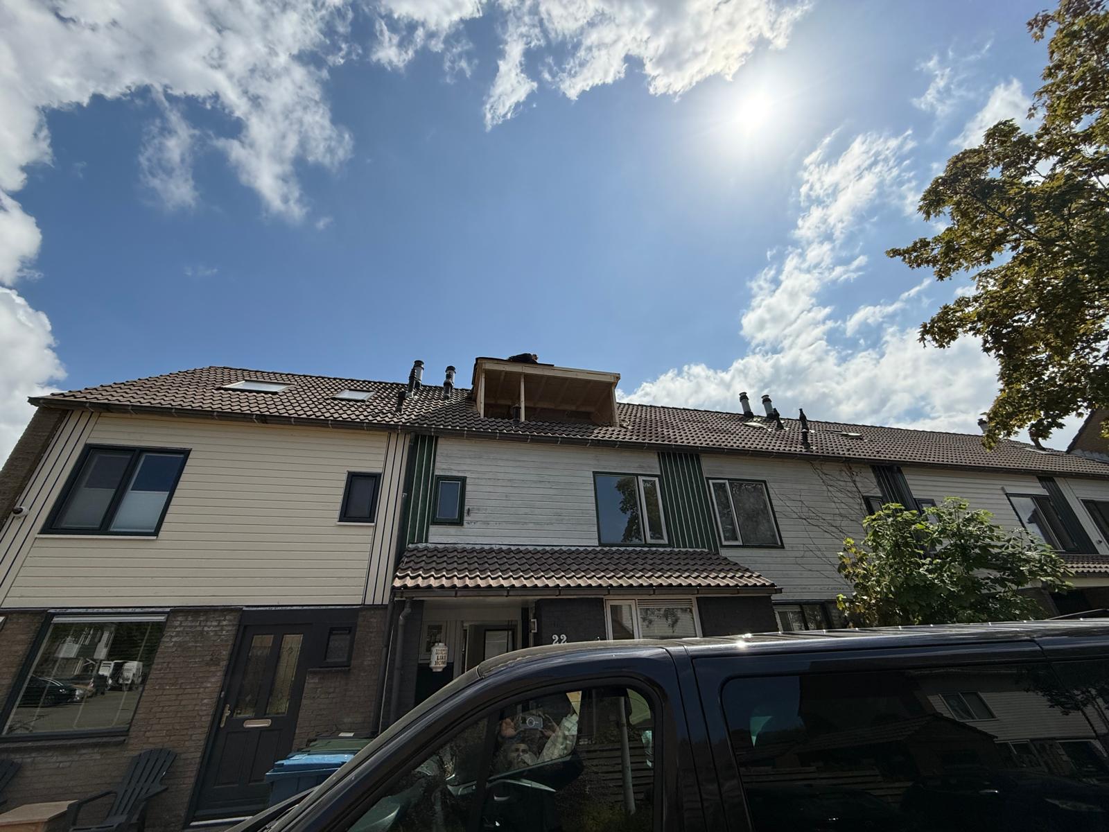 Rij woningen met dakkapellen onder een blauwe lucht