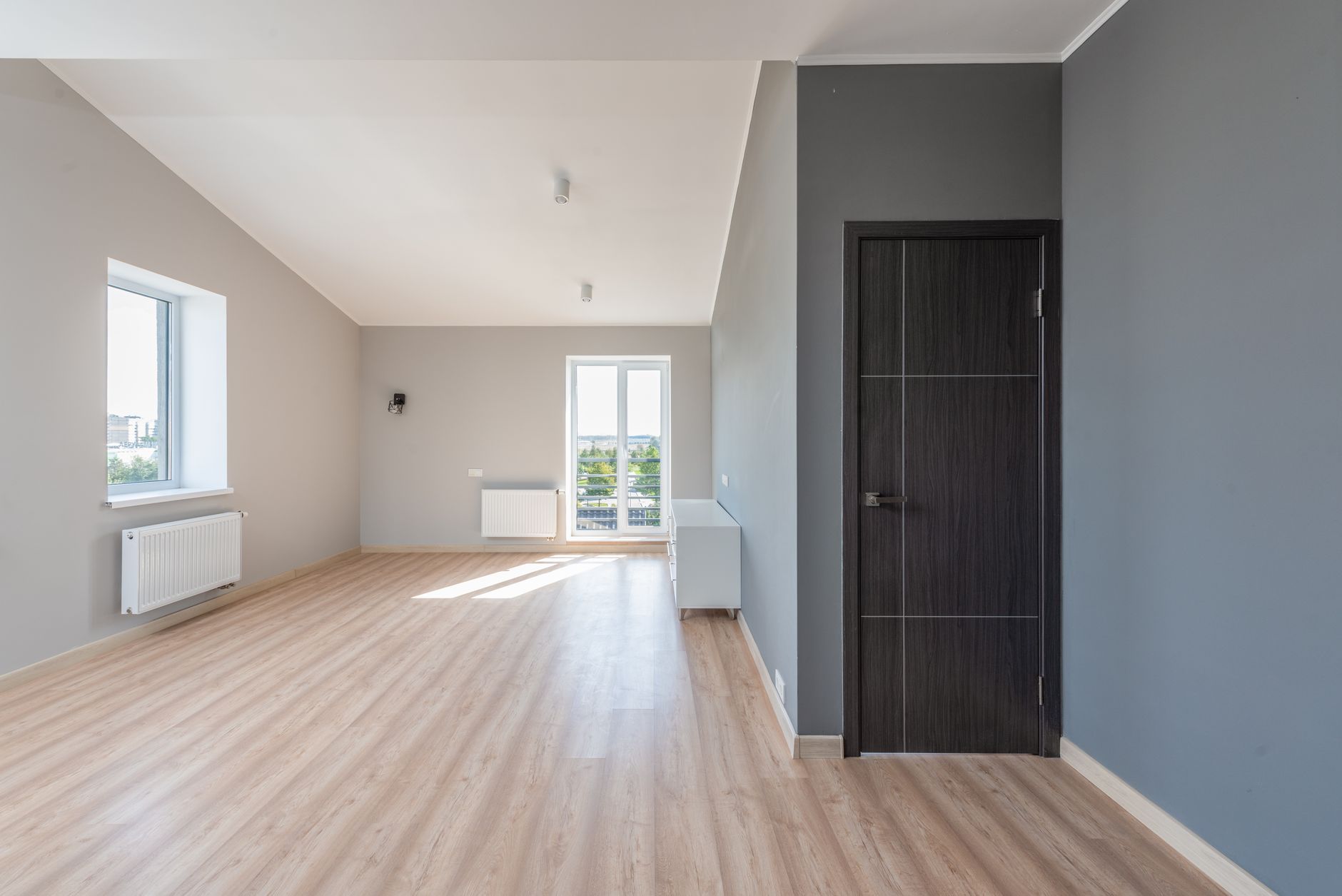 Lege kamer met lichte houten vloer en grijze wand