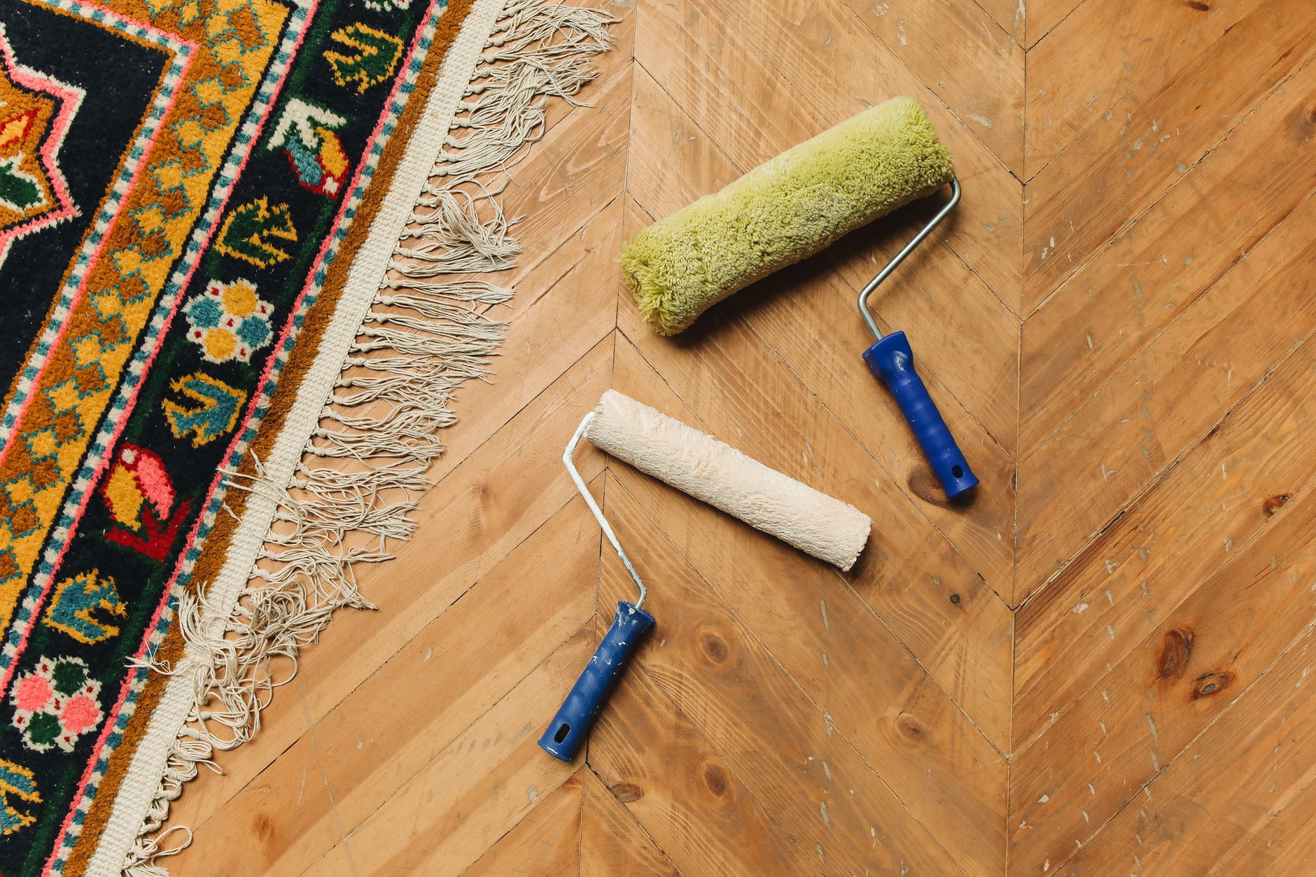 Verfrollers op een houten vloer naast een kleed